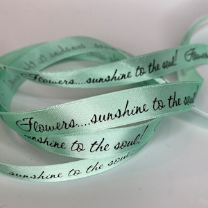 May include: A roll of light green satin ribbon with the text "Flowers... sunshine to the soul!" printed in black.
