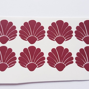 Op de afbeelding: Acht bordeauxrode vinyl stickers van schelpen. Elke sticker is ongeveer 5 cm in diameter.