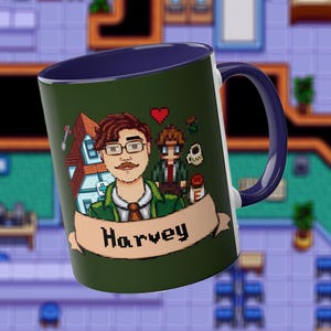 May include: A dark green ceramic mug with a dark blue interior and handle. The exterior features a pixel art illustration of a character with brown hair, glasses, and a mustache, wearing a green jacket, with the name Harvey printed on a banner.