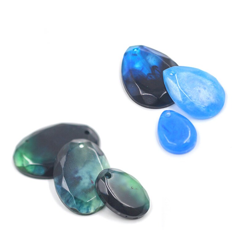 May include: Assortment of agate gemstone pendants in various shapes and colours, including black, green, and blue. The pendants have a smooth, polished finish and are perfect for jewellery making.