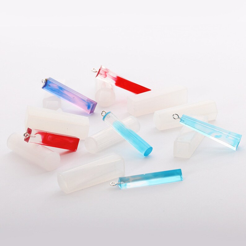 May include: Assortment of colorful resin pendant blanks with silver jump rings. The blanks are rectangular and have a marbled effect. Some are blue, red, and pink.