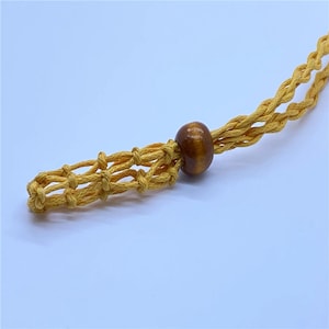 May include: A yellow macrame cord necklace with a brown wooden bead.