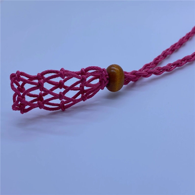 May include: A pink crocheted net bag with a wooden bead attached to a pink cord.