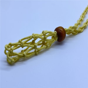 May include: A yellow macrame cord necklace with a brown wooden bead. The necklace is made with a knotting technique that creates a net-like pattern.