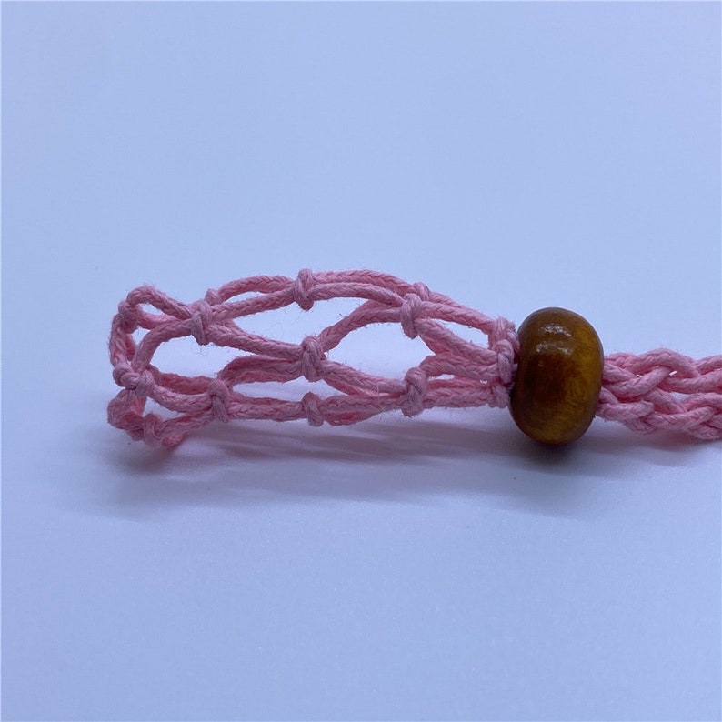May include: A pink crocheted net with a brown wooden bead attached to the end.