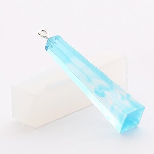 May include: A light blue resin pendant with a white swirl design. The pendant has a silver bail and is shaped like a long, thin rectangle with a hexagonal base.