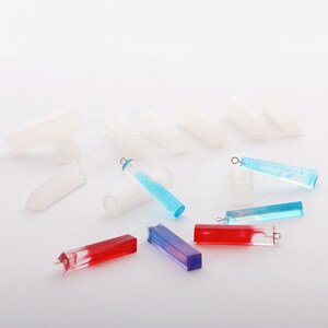 May include: A set of clear silicone molds for making rectangular resin pendants. The molds are shown with finished resin pendants in blue, red, and purple.