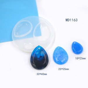 May include: A silicone mould for making resin pendants. The mould has three cavities, each shaped like a teardrop. The mould is shown with three finished resin pendants, one blue, one light blue, and one dark blue with white swirls. The pendants measure 18 x 25 mm, 25 x 35 mm, and 30 x 40 mm.