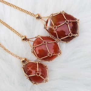 Puede incluir: Tres collares de oro con piedras de cornalina encerradas en un diseño de jaula de oro. Las piedras son de color rojo anaranjado oscuro.