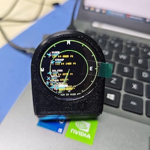 Op de afbeelding: Een zwart, rond elektronisch apparaat met een scherm dat een radarinterface weergeeft. Het display toont vluchtgegevens, waaronder vliegtuigidentificaties, snelheden in knopen en hoogtes in voet, met een kompasoverlay.