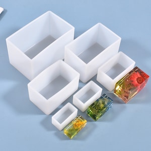 May include: Set of six clear silicone molds for resin casting. The molds are rectangular and range in size. The image shows the molds with finished resin castings inside.