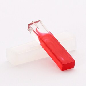 May include: A clear rectangular pendant with a red swirl inside. The pendant is sitting on a white silicone mold.