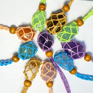 May include: A collection of colorful crystal stones wrapped in macrame string. Each stone is a different color and shape, and they are all strung together with a wooden bead.