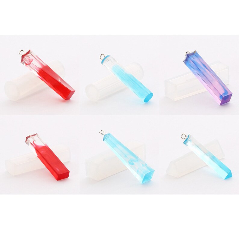 May include: Six clear resin pendant molds with a metal bail. The molds are filled with red, blue, and purple resin. The molds are sitting on a white surface.