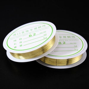 Puede incluir: Dos carretes de alambre de cobre dorado para la elaboraci&oacute;n de joyas. Los carretes est&aacute;n etiquetados con "Import Jewelry Copper Wire for Jewelry" y "0.2 mm".