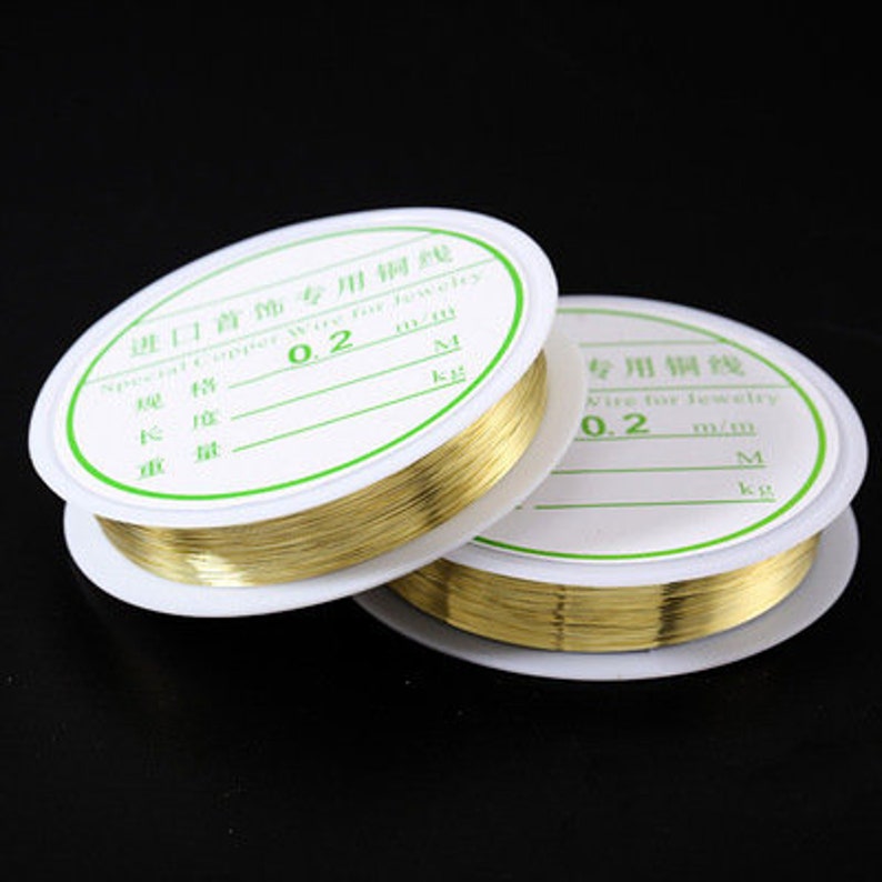 Puede incluir: Dos carretes de alambre de cobre dorado para la elaboraci&oacute;n de joyas. Los carretes est&aacute;n etiquetados con "Import Jewelry Copper Wire for Jewelry" y "0.2 mm".
