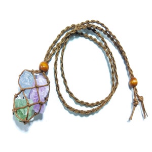 以下が含まれることがあります： 木製のビーズとクリスタルペンダントが付いた茶色の紐のネックレス。ペンダントは、薄い青、紫、緑の3つのクリスタルを保持する結び目のネットです。