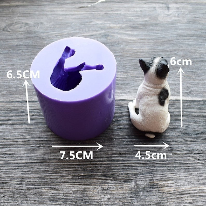 May include: A purple silicone mold and a small dog figurine. The mold is cylindrical, 6.5 cm tall and 7.5 cm wide, with a dog-shaped cavity. The dog figurine is white with black markings, 6 cm tall and 4.5 cm wide.