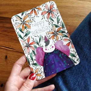 Kleurrijke en vrolijke verjaardagskaart met een eenhoorn op een bloemenachtergrond, met de hand geschilderde originele illustratie