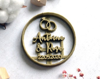 May include: Gold-colored 3D printed cookie cutter with the names "Antonia & Rose" and the date "22.05.2020" inside a circle. Two interlocking rings are at the top of the cutter.