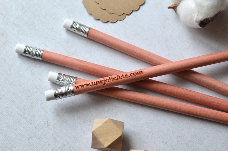 Puede incluir: Cuatro l&aacute;pices de madera con gomas blancas y puntas de metal plateado. Los l&aacute;pices est&aacute;n apilados uno encima del otro. El l&aacute;piz de arriba tiene el sitio web "www.unejoliefete.com" grabado en &eacute;l.