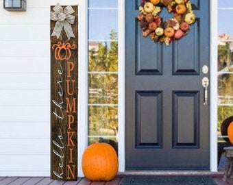 May include: A fall-themed front porch with a black door, a pumpkin wreath, and two orange pumpkins. A wooden sign with a bow and the words "hello there PUMPKIN" is on the left. A small wooden stool holds a pumpkin.