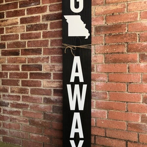 May include: A black wooden sign with white letters spelling "G AWAY" with the state of Missouri outline in white above the "G".
