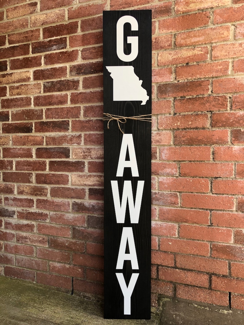 May include: A black wooden sign with white letters spelling "G AWAY" with the state of Missouri outline in white above the "G".