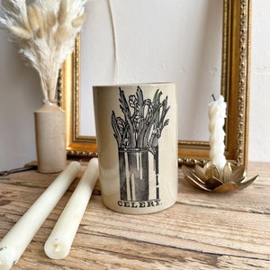 May include: A ceramic jar with a black and white illustration of celery. The jar is labeled "CELERY".