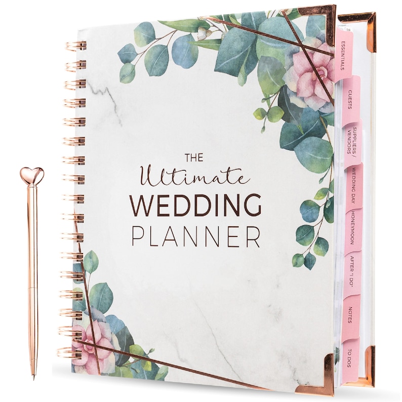 May include: A white and gold wedding planner with a marble pattern and floral design. The planner has tabs for guests, essentials, suppliers, vendors, wedding day, honeymoon, after "I do", notes, and to dos.