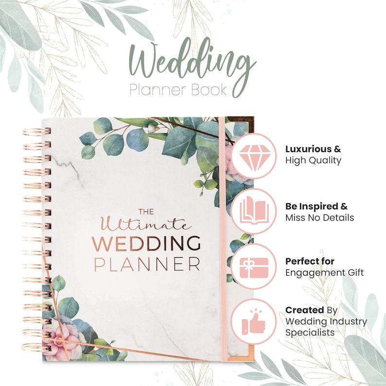 May include: A white and rose gold wedding planner with a marble and floral design. The cover says "The Ultimate Wedding Planner".