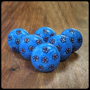 Peut inclure: Cinq boutons de cabinet en céramique bleue avec des motifs floraux blancs et rouges.