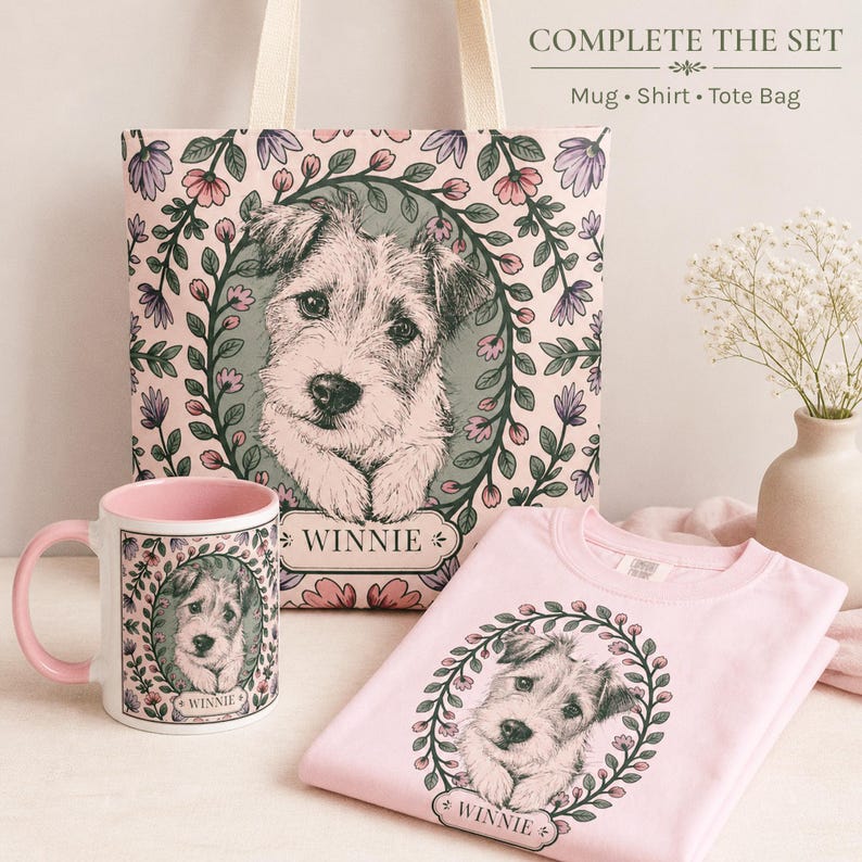 May include: A pink mug, t-shirt, and tote bag set featuring a dog portrait within a floral wreath. The tote bag and t-shirt are light pink, while the mug has a pink interior and handle. The word "WINNIE" is printed on each item.