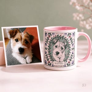 May include: A white ceramic mug with a pink interior and handle, featuring a dog portrait surrounded by a floral wreath. A photograph of the same dog is next to the mug. The mug has the name "Winnie" on it.