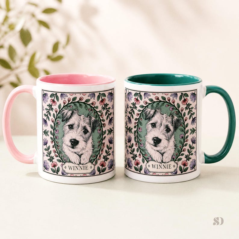 May include: Two white ceramic mugs with a dog portrait. One mug has a pink handle and interior, the other has a green handle and interior. Each mug features a floral wreath design around the dog portrait, with the name "Winnie" below.