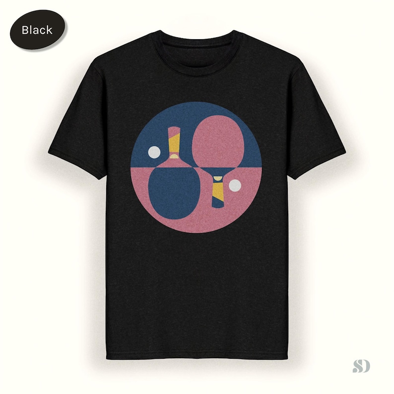 K&ouml;nnte beinhalten: Schwarzes T-Shirt mit einem grafischen Design von zwei Tischtennisschl&auml;gern und zwei B&auml;llen in einem Kreis. Der Kreis ist in blaue und rosa Abschnitte unterteilt. Die Schl&auml;ger haben gelbe Akzente.
