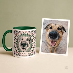 May include: A white ceramic mug with a green handle and rim, featuring a dog portrait surrounded by floral elements. The mug has the name "MOOSE" below the dog's portrait. A photo of the dog is next to the mug.
