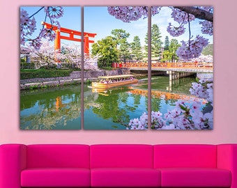 May include: A three-panel canvas print featuring a scenic view of a Japanese river with a traditional red torii gate, cherry blossoms, and a boat filled with people. The water reflects the surrounding trees and sky.