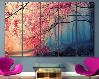 Op de afbeelding: Een meerdelige canvas print die een mistige bos scène toont met roze bloesems aan de bomen. De print hangt aan een muur in een woonkamer met twee roze stoelen en een glazen salontafel.
