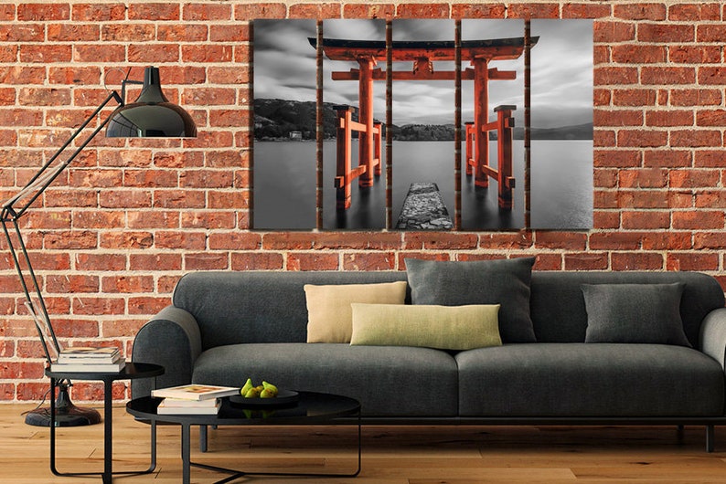 May include: A black and white photograph of a red Japanese Torii gate, a traditional gateway, standing in a body of water. The gate is partially submerged in the water, and the water is calm and reflective. The sky is cloudy and overcast.