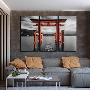 May include: A three-panel canvas print featuring a red Japanese Torii gate, a traditional gateway, standing in a body of water. The gate is surrounded by a black and white landscape with a cloudy sky.