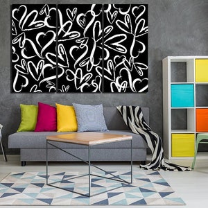Puede incluir: Un interior de sala de estar con un sof&aacute; gris, una silla blanca, una silla verde, una mesa de caf&eacute; de madera y una estanter&iacute;a blanca con contenedores de almacenamiento coloridos. Una impresi&oacute;n de lienzo en blanco y negro con un patr&oacute;n de corazones blancos sobre un fondo negro cuelga de la pared.