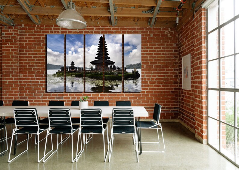 May include: A three-panel canvas print featuring a scenic view of a traditional Balinese temple on a small island in a lake. The temple is surrounded by lush greenery and the water reflects the sky and clouds.