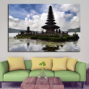 May include: A black temple with a tiered roof sits on a small island in a lake. The temple is surrounded by lush greenery and the water is calm and reflective. The sky is blue with white clouds.