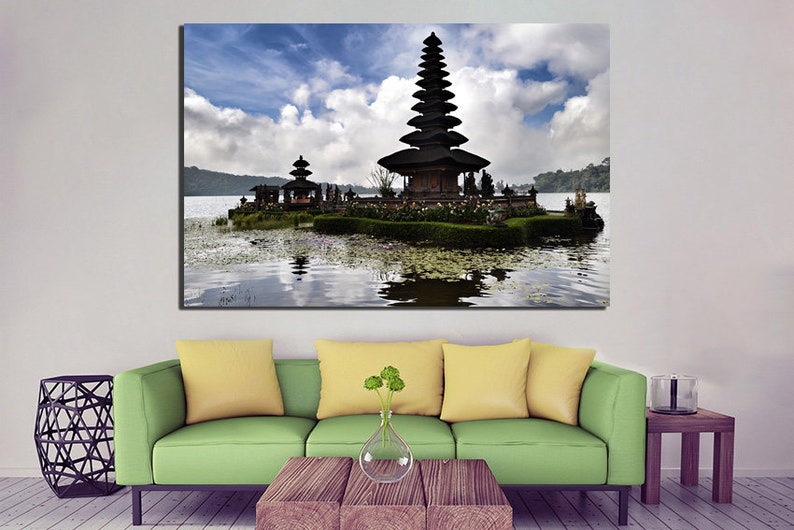 May include: A black temple with a tiered roof sits on a small island in a lake. The temple is surrounded by lush greenery and the water is calm and reflective. The sky is blue with white clouds.
