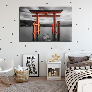 May include: A black and white photograph of a red torii gate, a traditional Japanese gateway, standing in a body of water. The gate is surrounded by water and a cloudy sky.