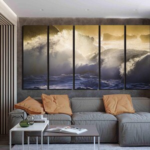May include: A living room interior with a gray sectional sofa and a set of four canvas prints depicting crashing ocean waves with a golden glow.