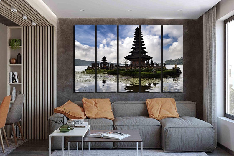 May include: A multi-panel canvas print featuring a scenic view of a traditional Balinese temple, Pura Ulun Danu Bratan, on a lake surrounded by lush greenery. The temple is a striking silhouette against a cloudy sky, reflected in the water.