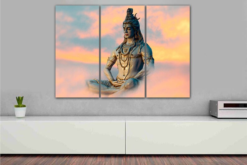 May include: A three-panel canvas print featuring a blue statue of Shiva meditating in a lotus position against a backdrop of pink and orange clouds.