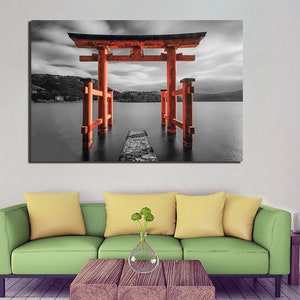 May include: A red Japanese Torii gate stands in a black and white landscape, with a stone path leading to it. The gate is reflected in the water, creating a symmetrical image.